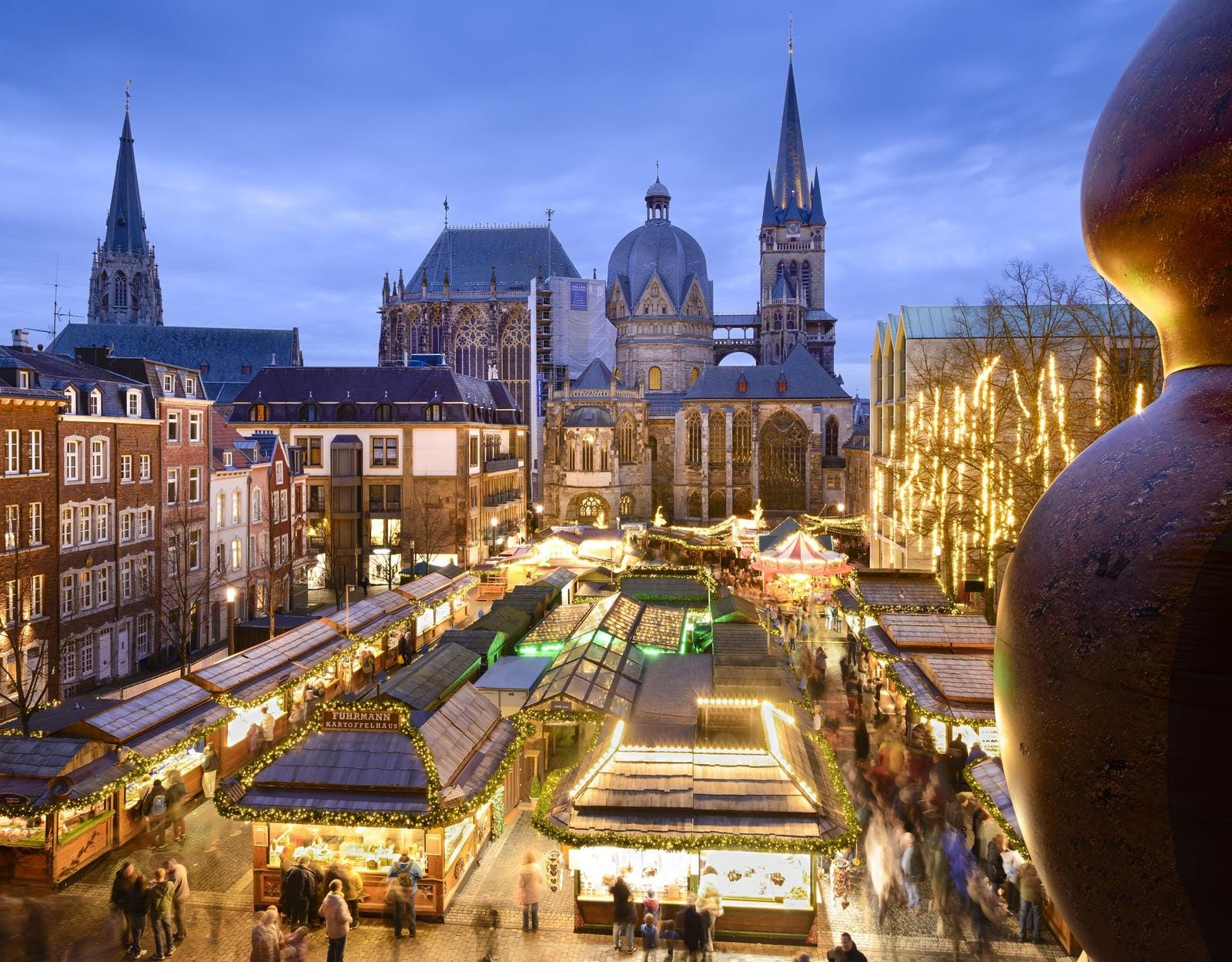 Weihnachtsmarkt in Aachen mit Dom und Lichterglanz bei Dämmerung.