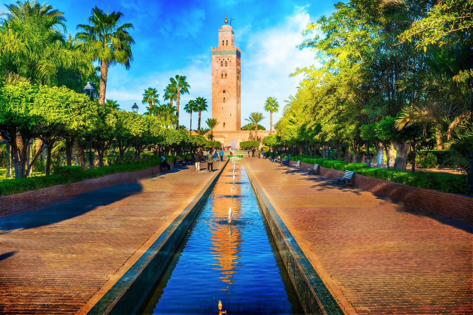 Koutoubia-Moschee in Marrakesch, Marokko, mit Palmen und Brunnen im Vordergrund.