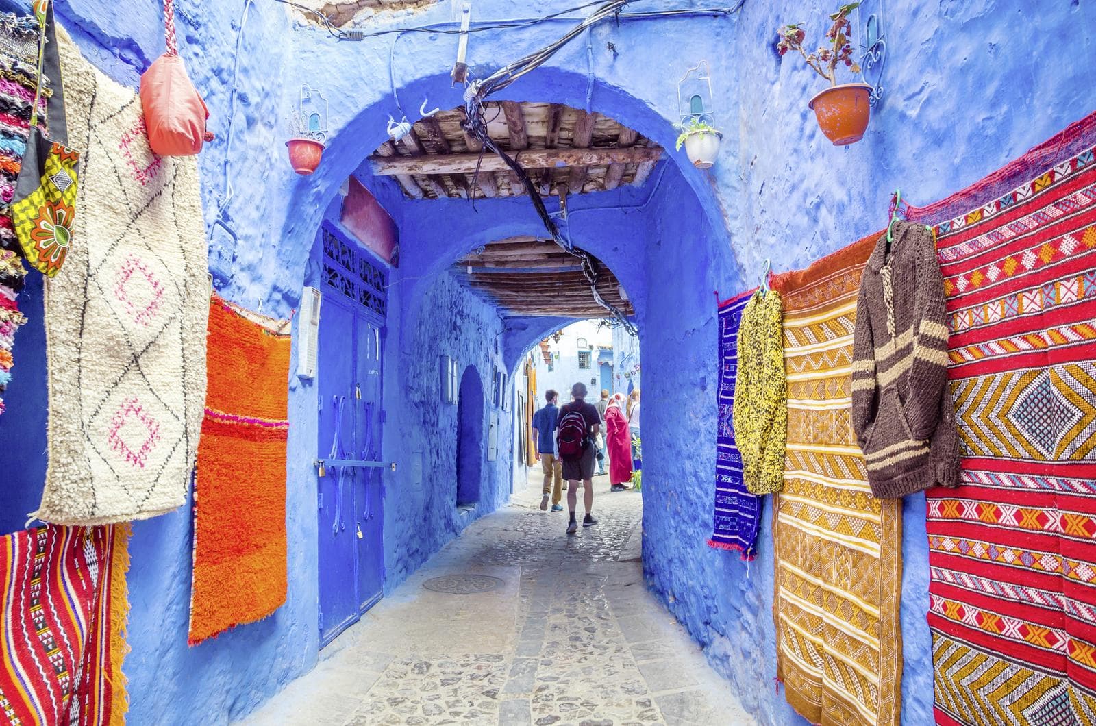 In Chefchaouen führen schmale, blau getünchte Gassen vorbei an bunten Teppichen und vermitteln das einzigartige Flair der „blauen Stadt“.