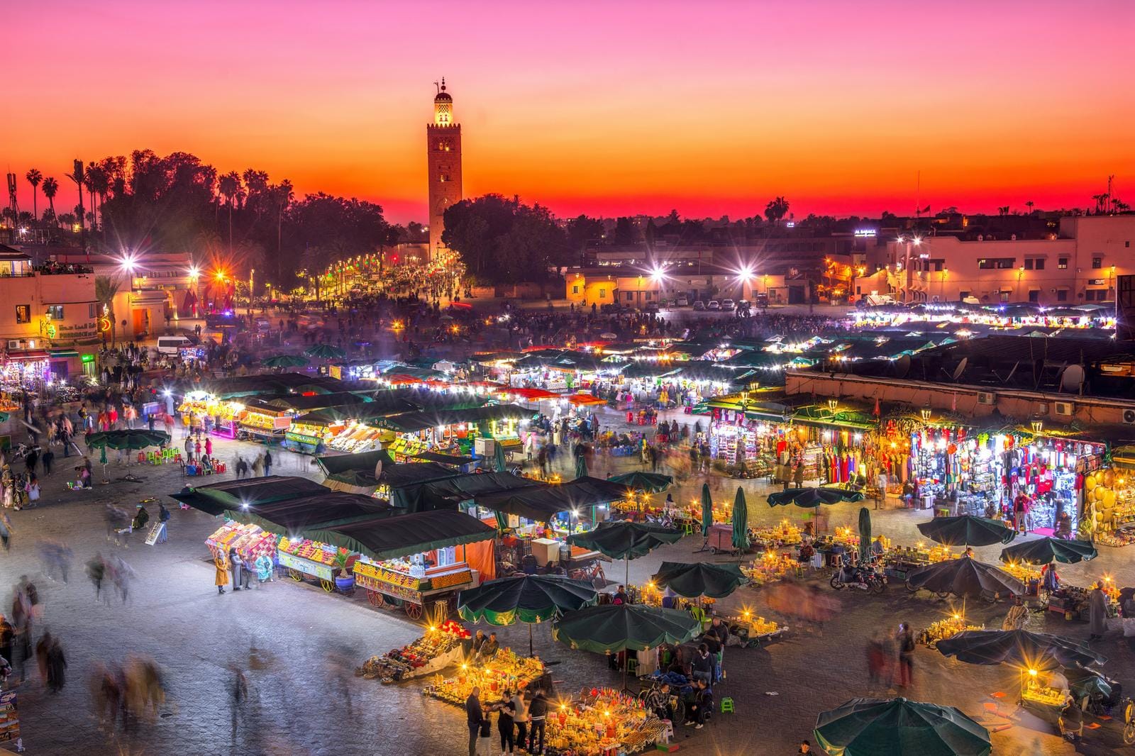 Bunter Markt in Marrakesch, Marokko, bei Sonnenuntergang mit belebter Atmosphäre.