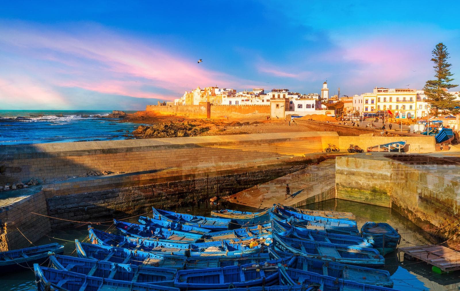 Blaue Boote im Hafen von Essaouira, Marokko, bei Sonnenuntergang; historische Altstadt.