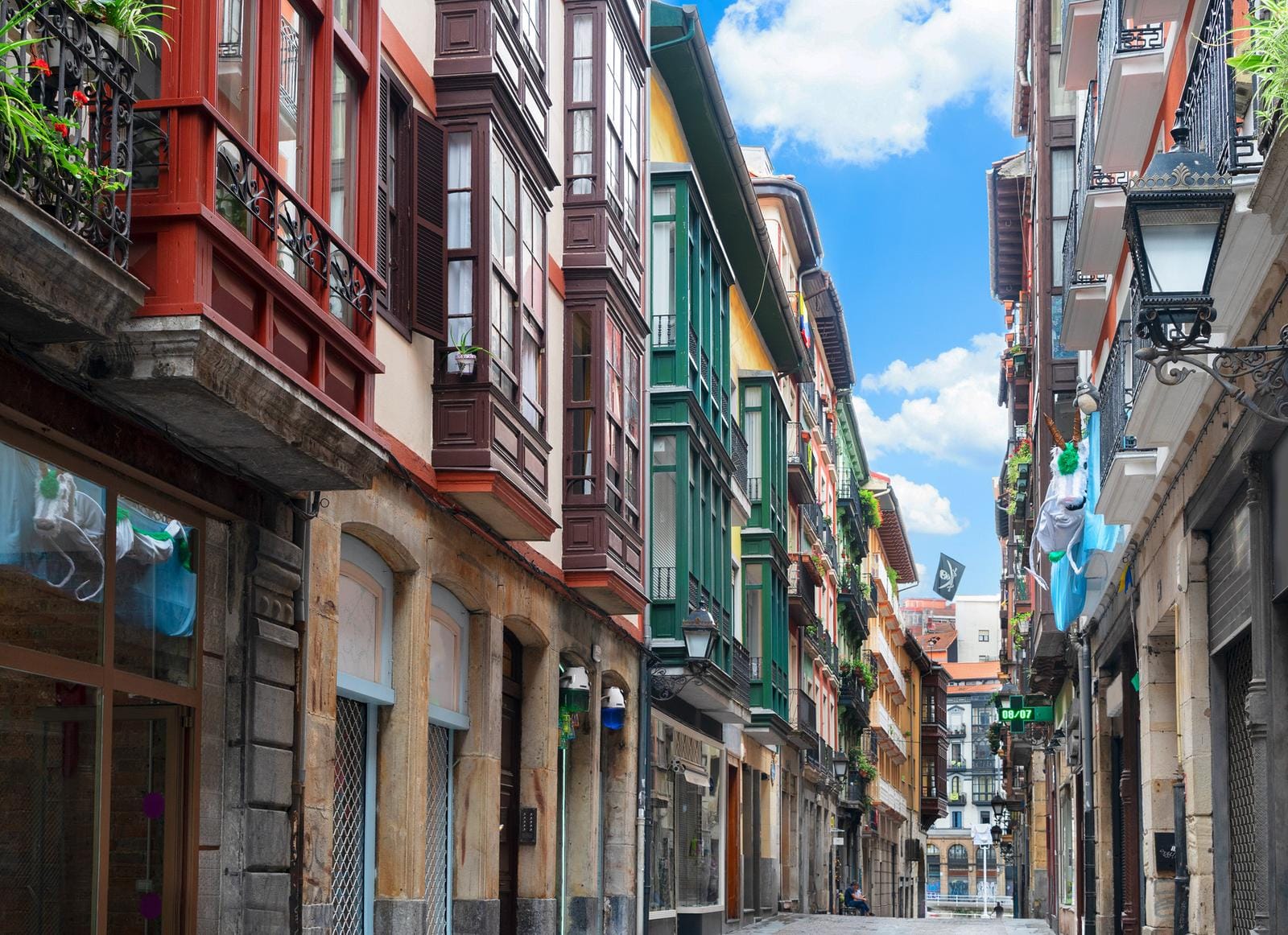 Bunte Altstadtgasse mit verzierten Fassaden in Bilbao, Spanien, unter blauem Himmel.