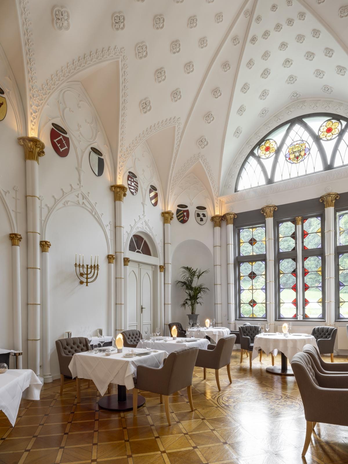 Elegantes Hotelrestaurant mit hohen Decken, Buntglasfenstern und klassischen Möbeln.