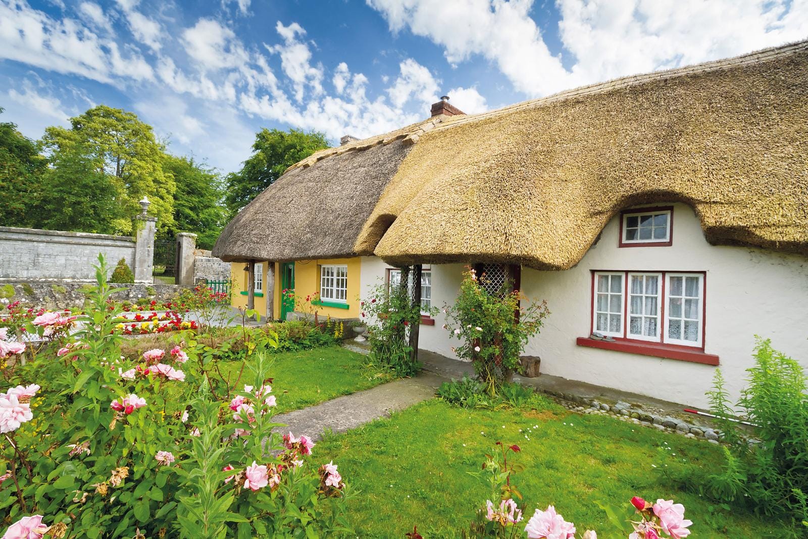 Maltesisches Bauernhaus mit Strohdach, bunten Fenstern und blühendem Garten.