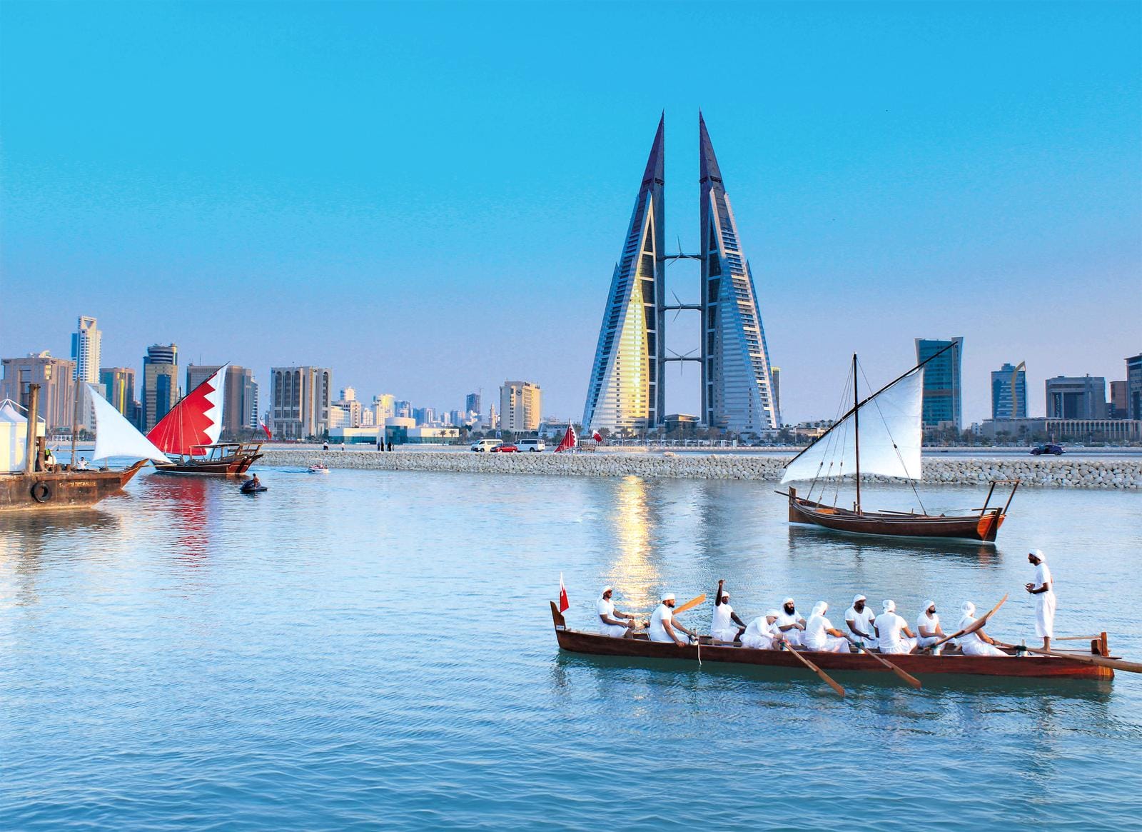 Moderne Skyline von Manama, Bahrain, mit traditionellen Booten auf ruhigem Wasser.