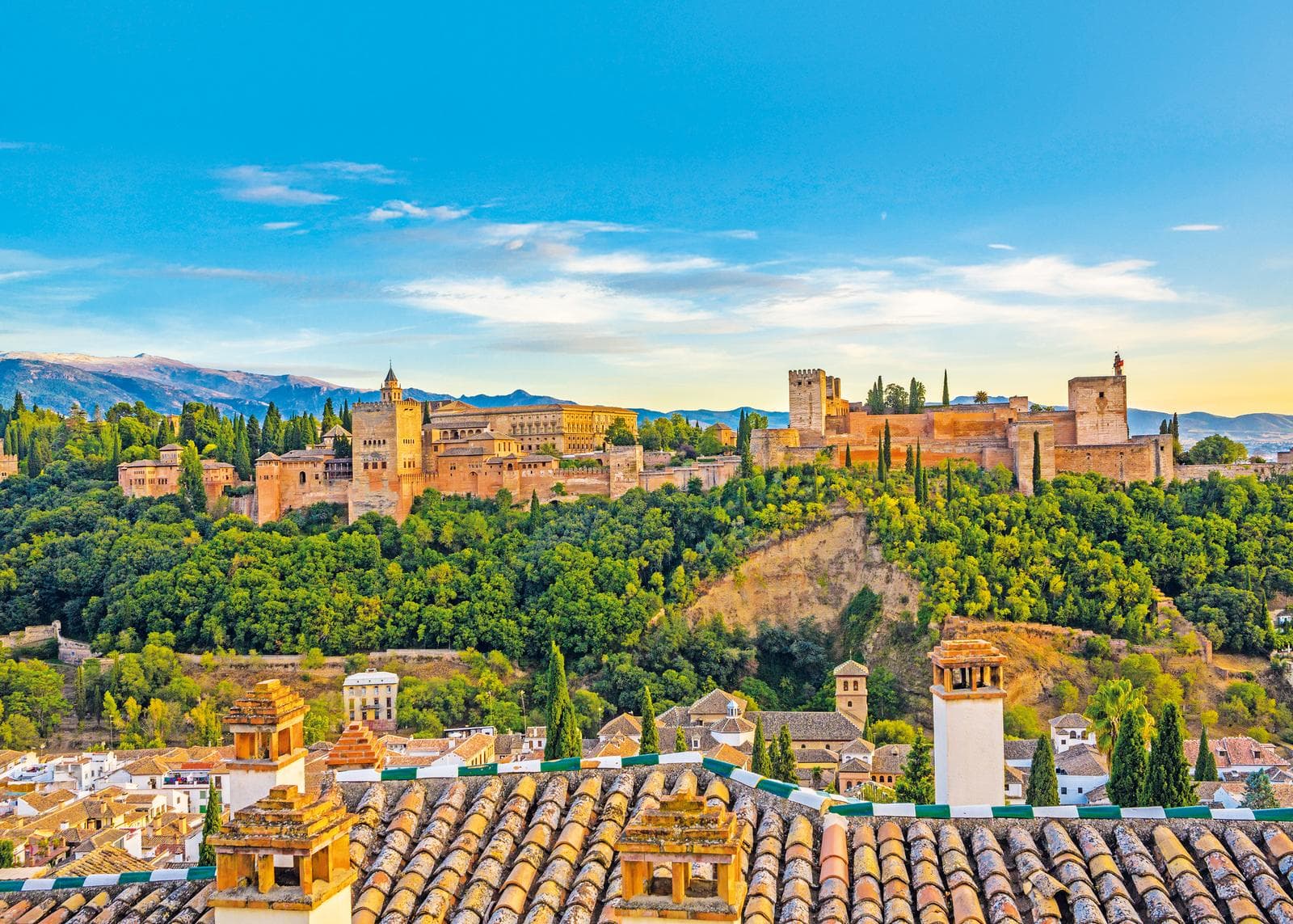 Alhambra in Granada, Spanien, auf Hügel mit Zypressen und blauem Himmel.
