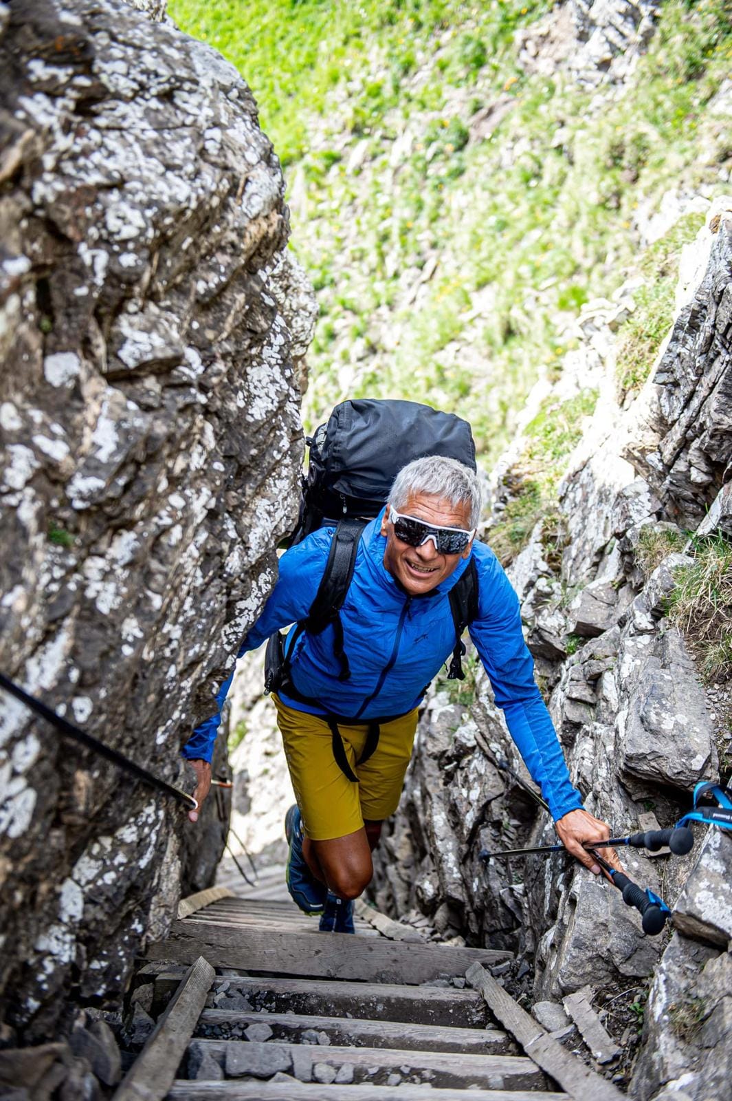 Mann wandert durch felsige Schlucht, sonniges Wetter, abenteuerliche Stimmung.