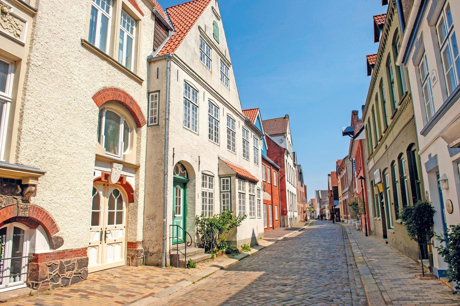 Charmante, gepflasterte Straße in Lübeck, Deutschland, gesäumt von charmanten Altbauten.