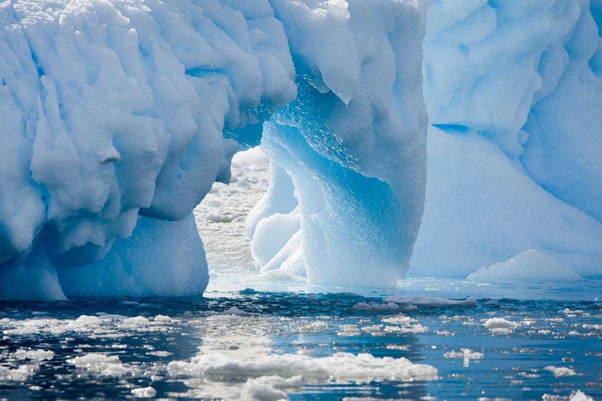 Blauer Eisberg über Wasser in einer Arktislandschaft.