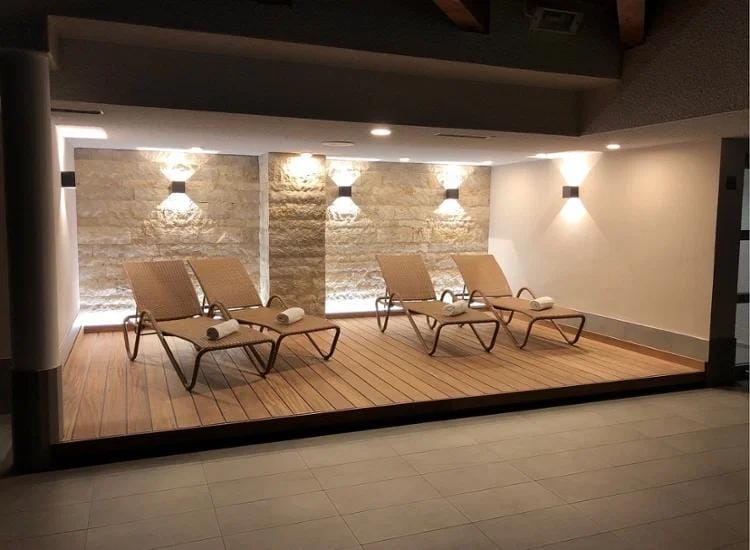 Eleganter Spa-Bereich mit vier Liegen, Holzboden und gedämpfter Beleuchtung.