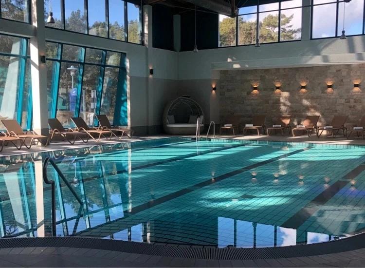 Moderner, lichtdurchfluteter Indoor-Pool mit Liegestühlen und Natursteinwand.