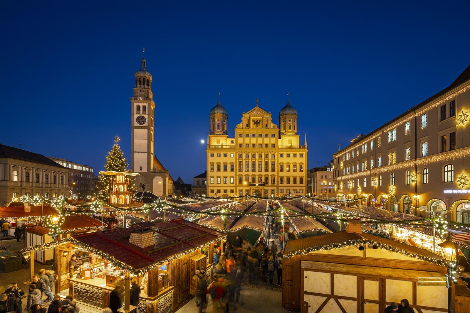 Weihnachtsmarkt in Augsburg, Deutschland, abends mit Lichterketten und Christbaum.