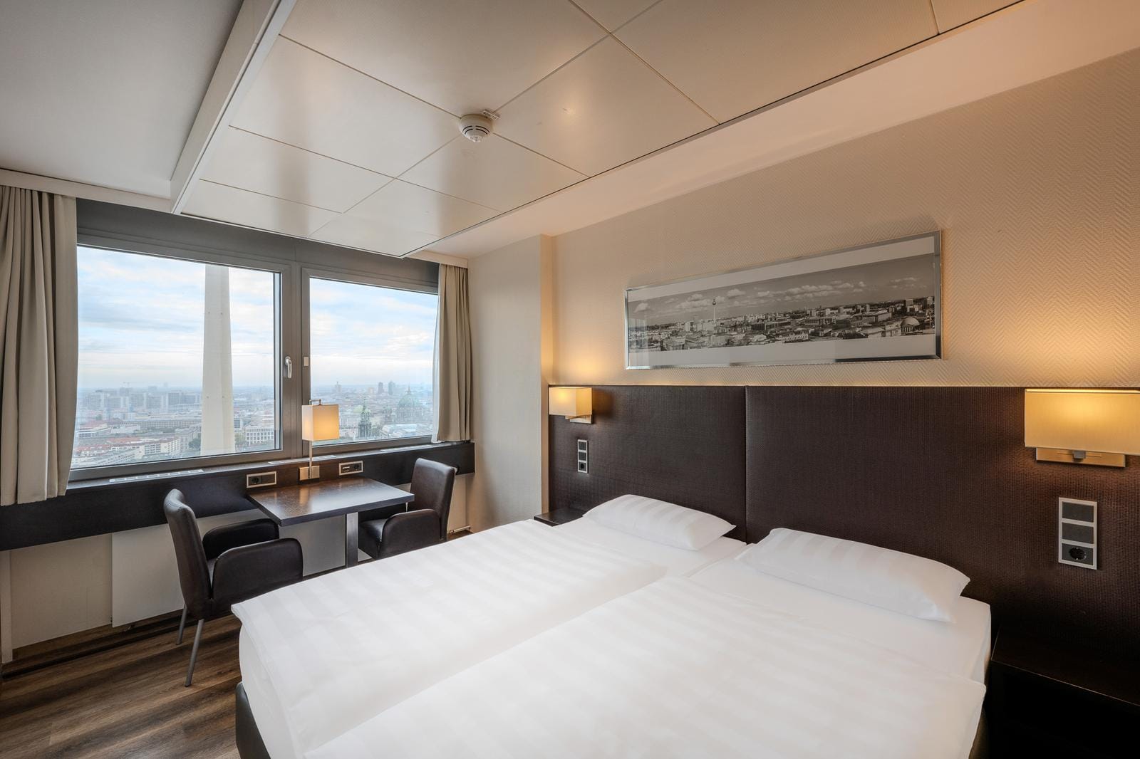 Modernes Hotelzimmer mit Doppelbett, großem Fenster, Stadtblick, Schreibtisch, stilvoll.