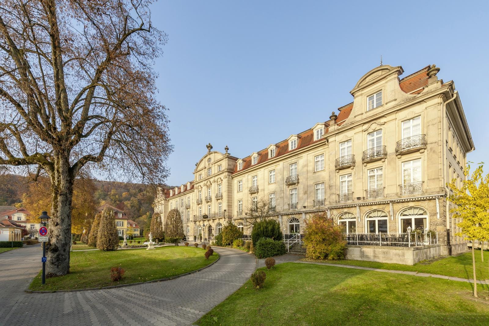 Historisches Hotel mit klassischer Fassade und gepflegtem Garten bei sonnigem Wetter.