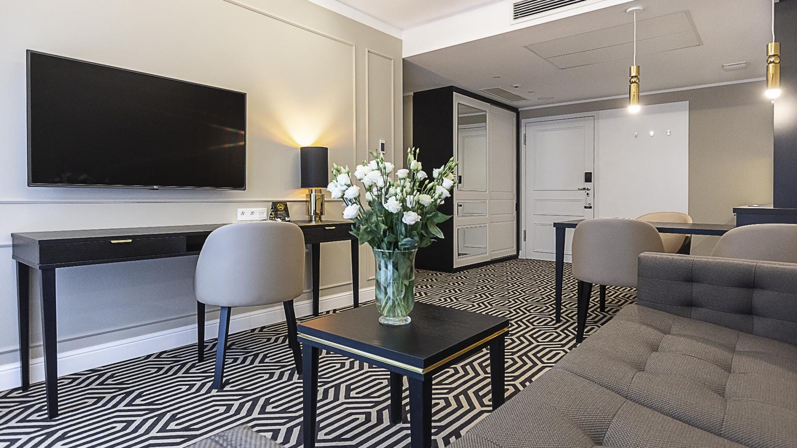 Elegantes Hotelzimmer in Beige und Grau mit modernem Dekor und Blumenarrangement.