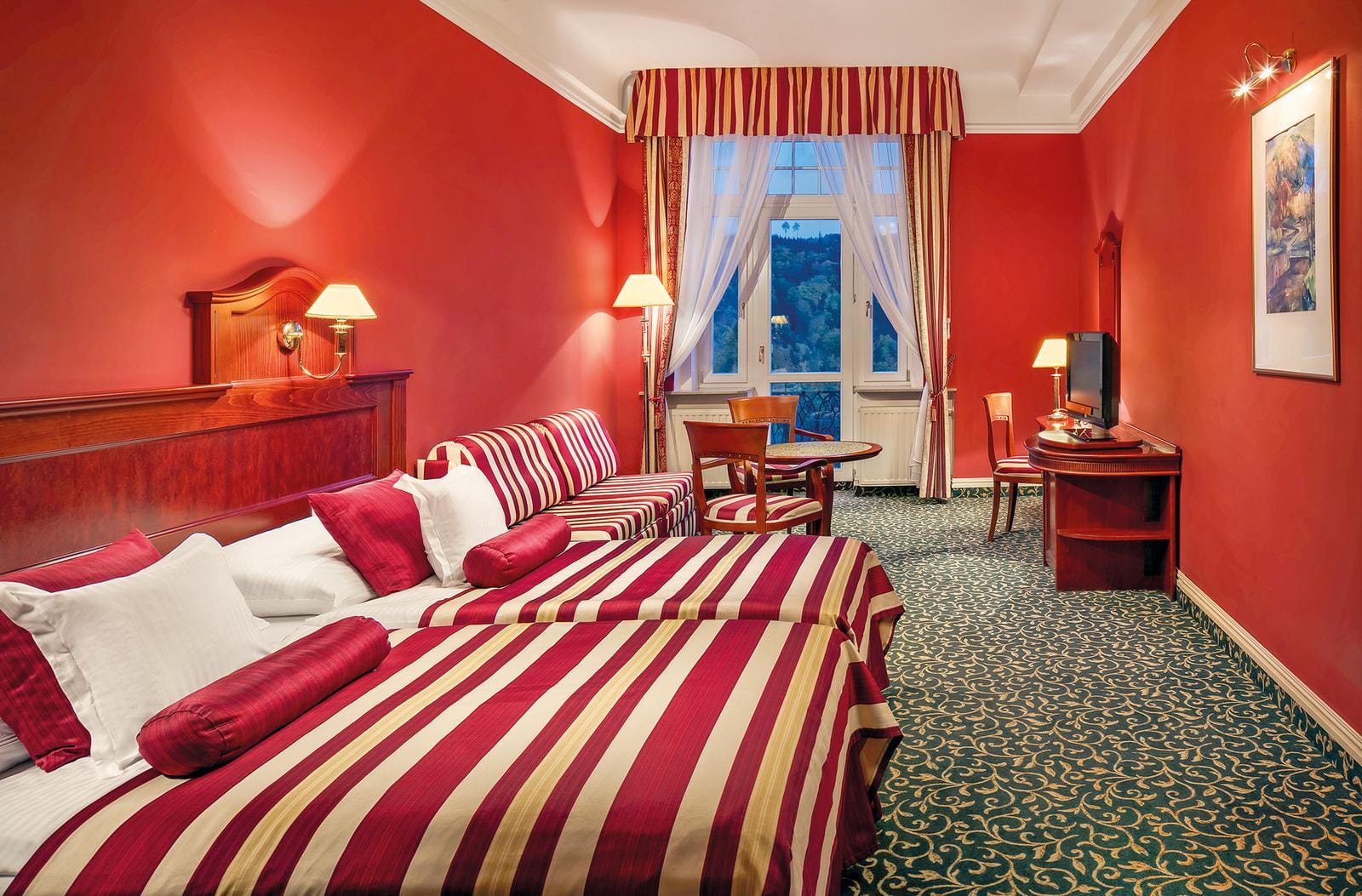 Hotelzimmer im klassischen Stil mit roten Wänden und gestreiften Stoffen.