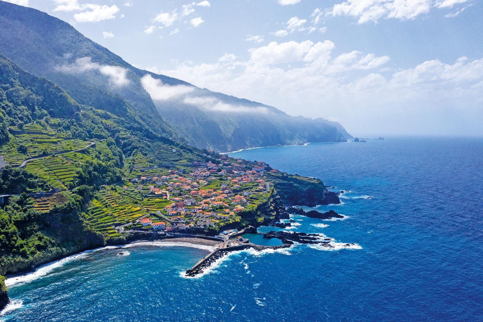 Küstenlandschaft auf Madeira, Portugal, mit terrassierten Feldern und blauem Ozean.