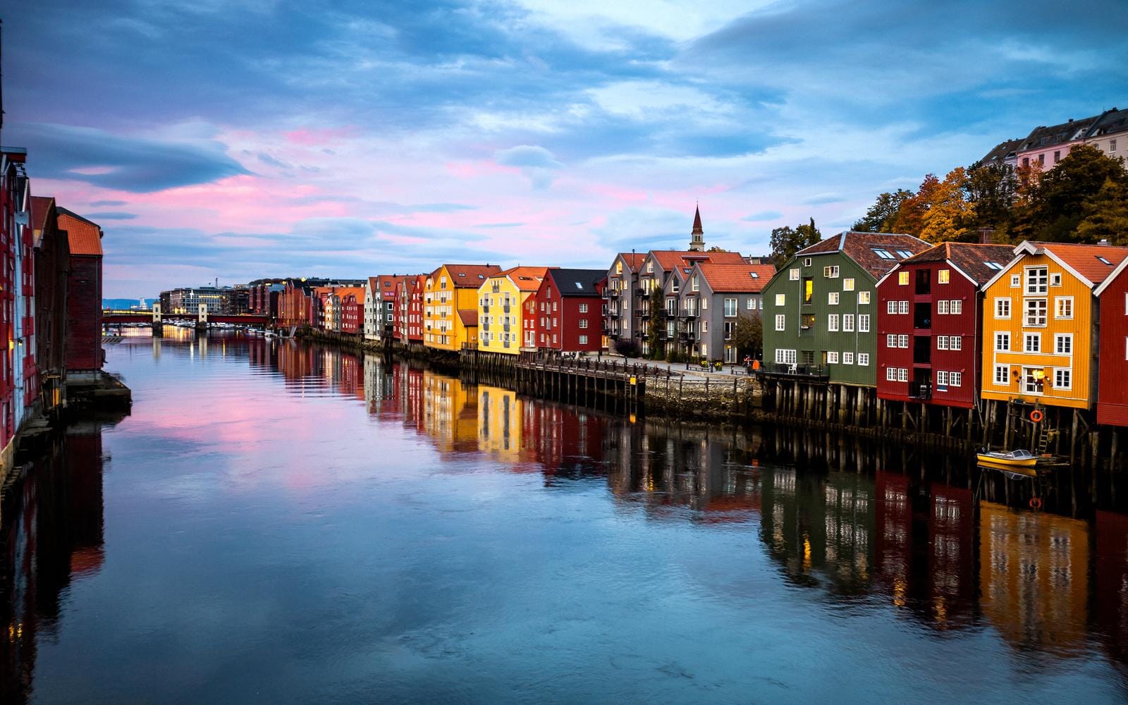 Bunte Hafenhäuser in Trondheim, Norwegen, spiegeln sich im ruhigen Wasser wider.