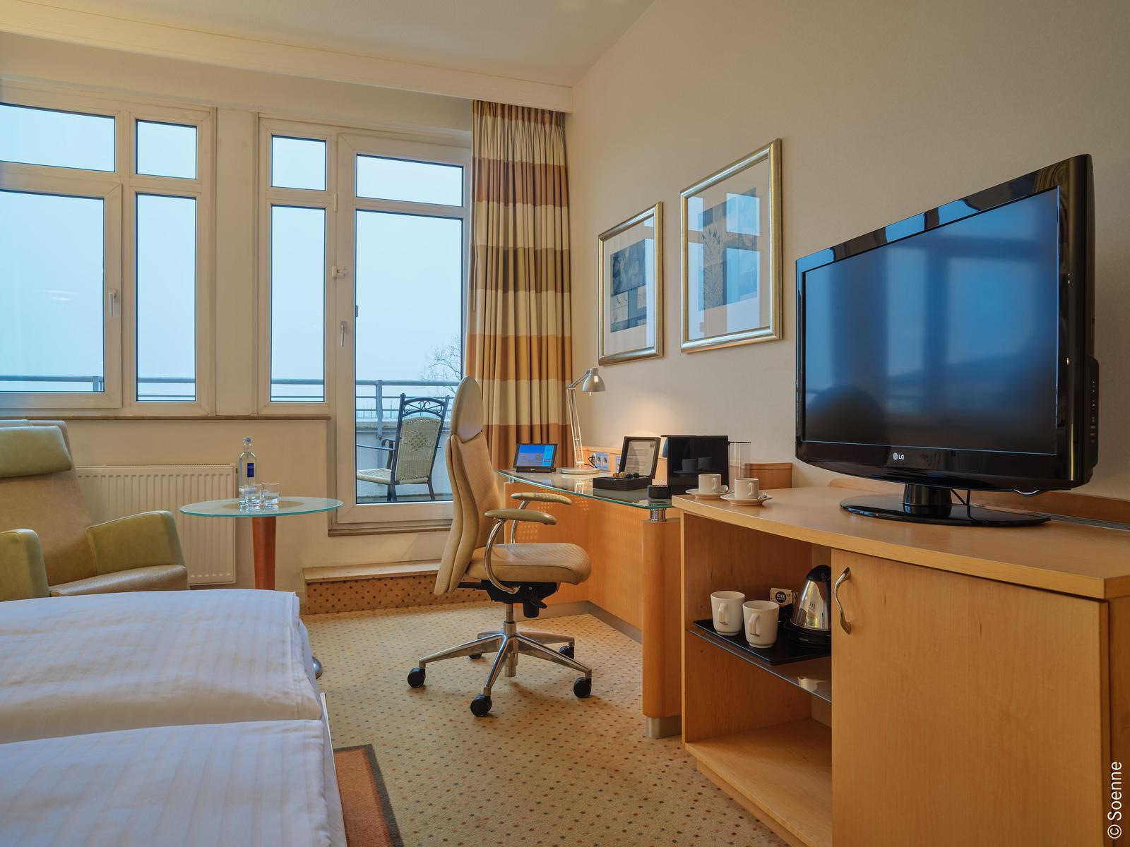 Modernes Hotelzimmer mit Meerblick, hellem Holz, beige Akzenten und Arbeitsbereich.