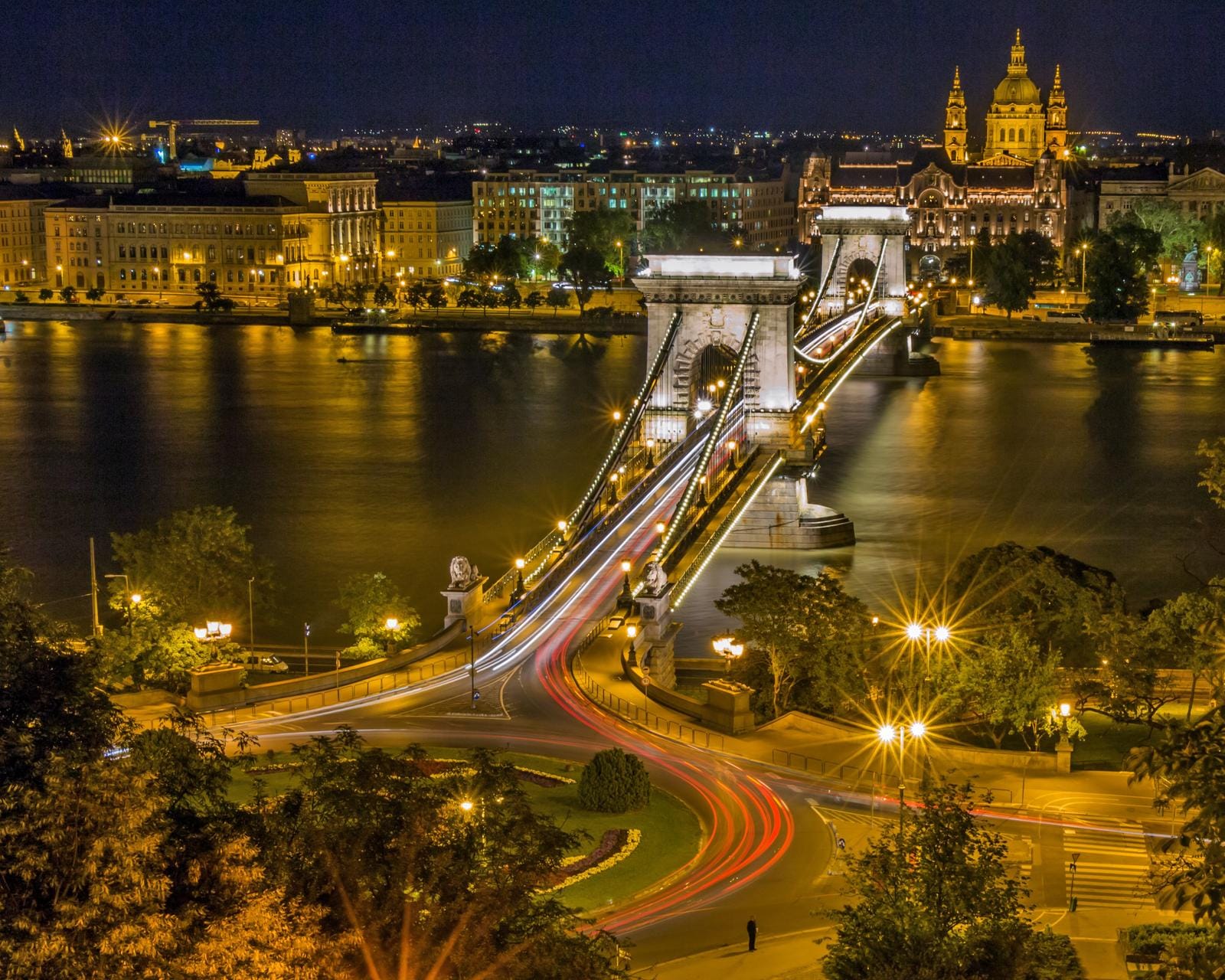 Nächtliche Ansicht der Kettenbrücke in Budapest, mit beleuchteten historischen Gebäuden.