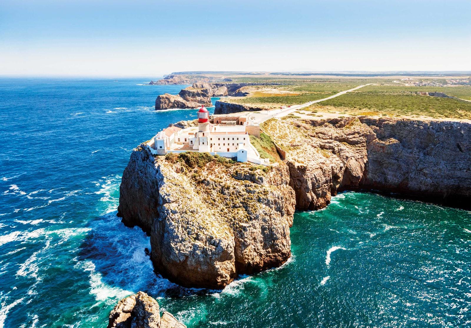 Leuchtturm auf Klippe über azurblauem Meer, Portugal, sonniger Himmel.