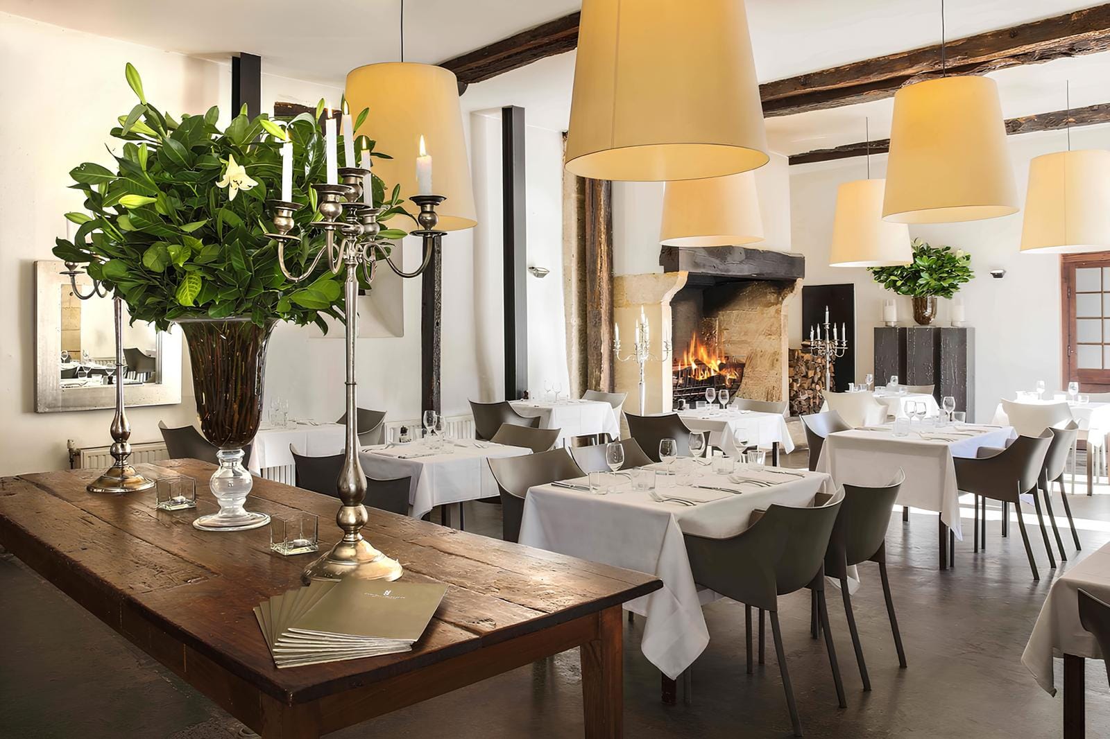 Elegantes Restaurant mit Kamin, weiĂźen Tischdecken und modernen, grauen StĂĽhlen.