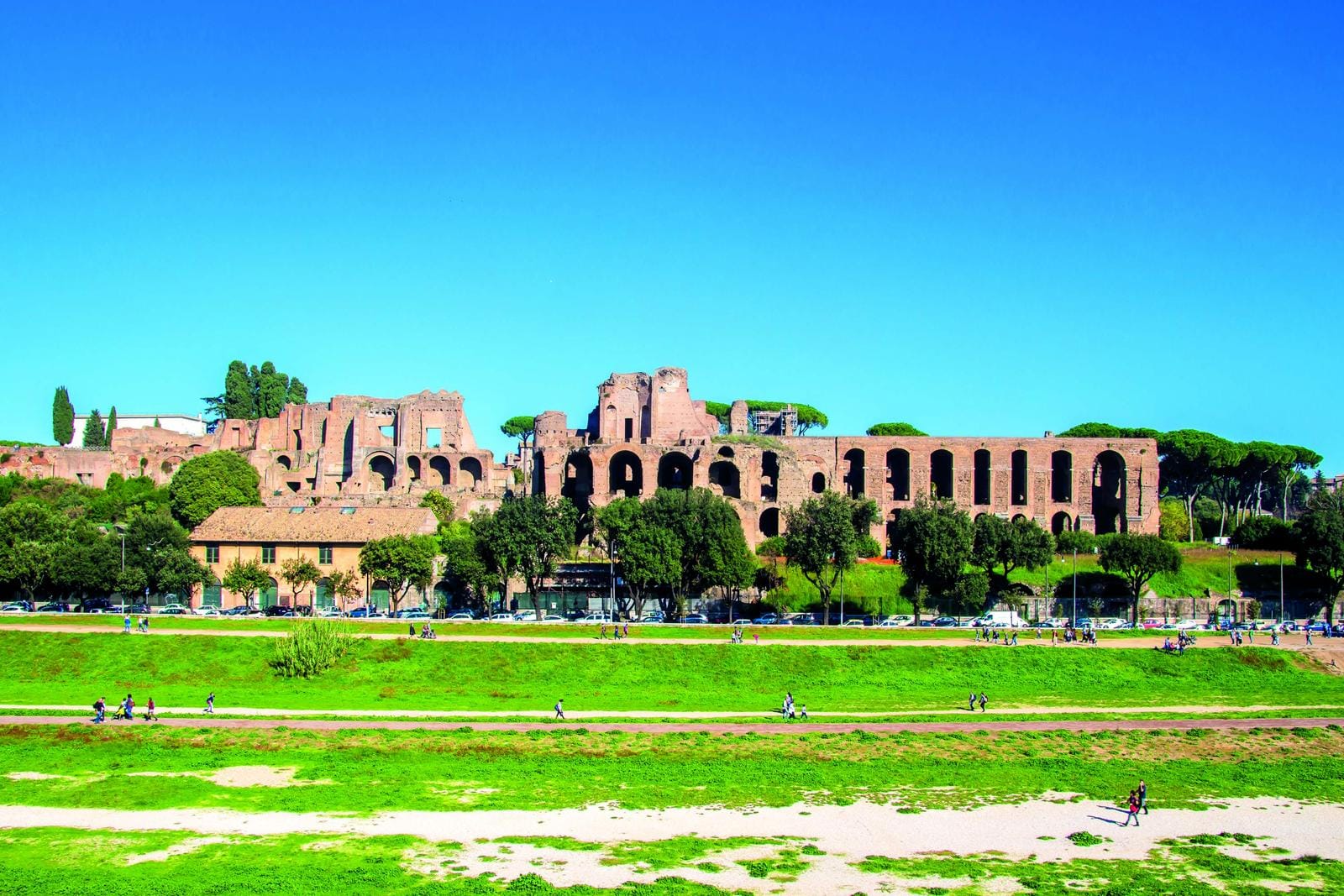 Römische Ruinen bei Sonnenschein, grüner Park im Vordergrund, historische Atmosphäre in Rom.
