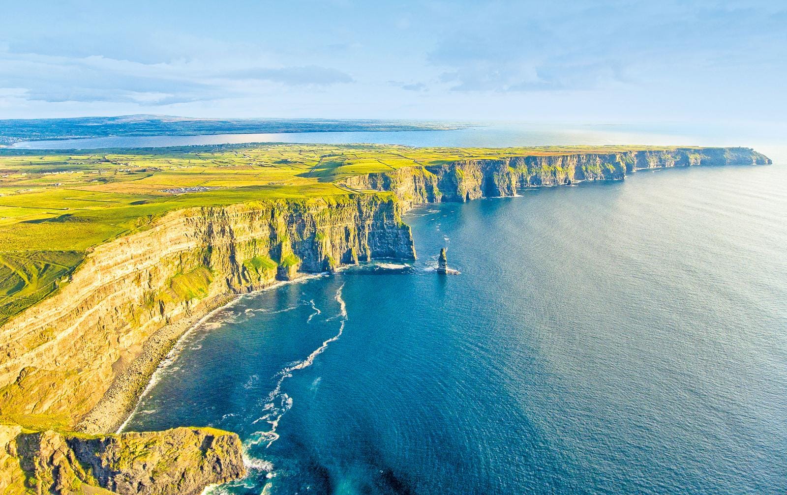 Malerische Klippen von Moher in Irland, grüne Wiesen und tiefblaues Meer.