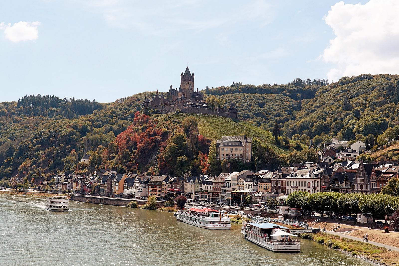 Blick auf die Reichsburg und Mosel in Cochem, Deutschland, umgeben von herbstlichen Wäldern.