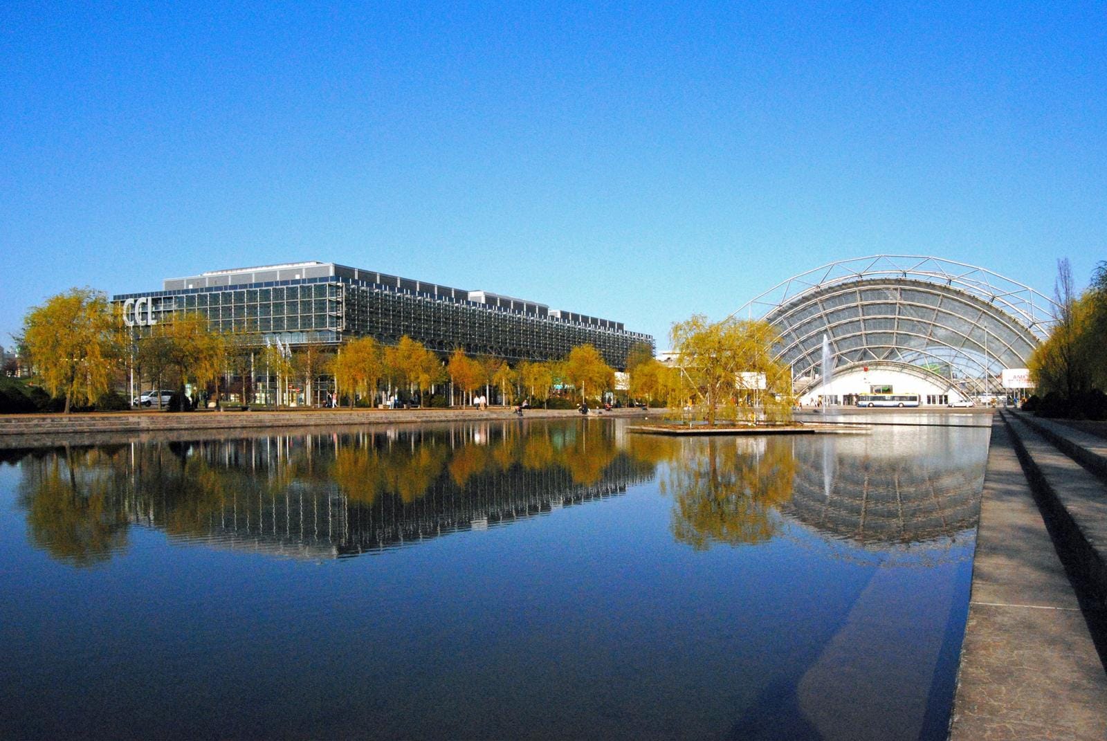 Moderne Messehalle mit Glaskuppel und reflektierendem Wasser, Leipzig, Deutschland.