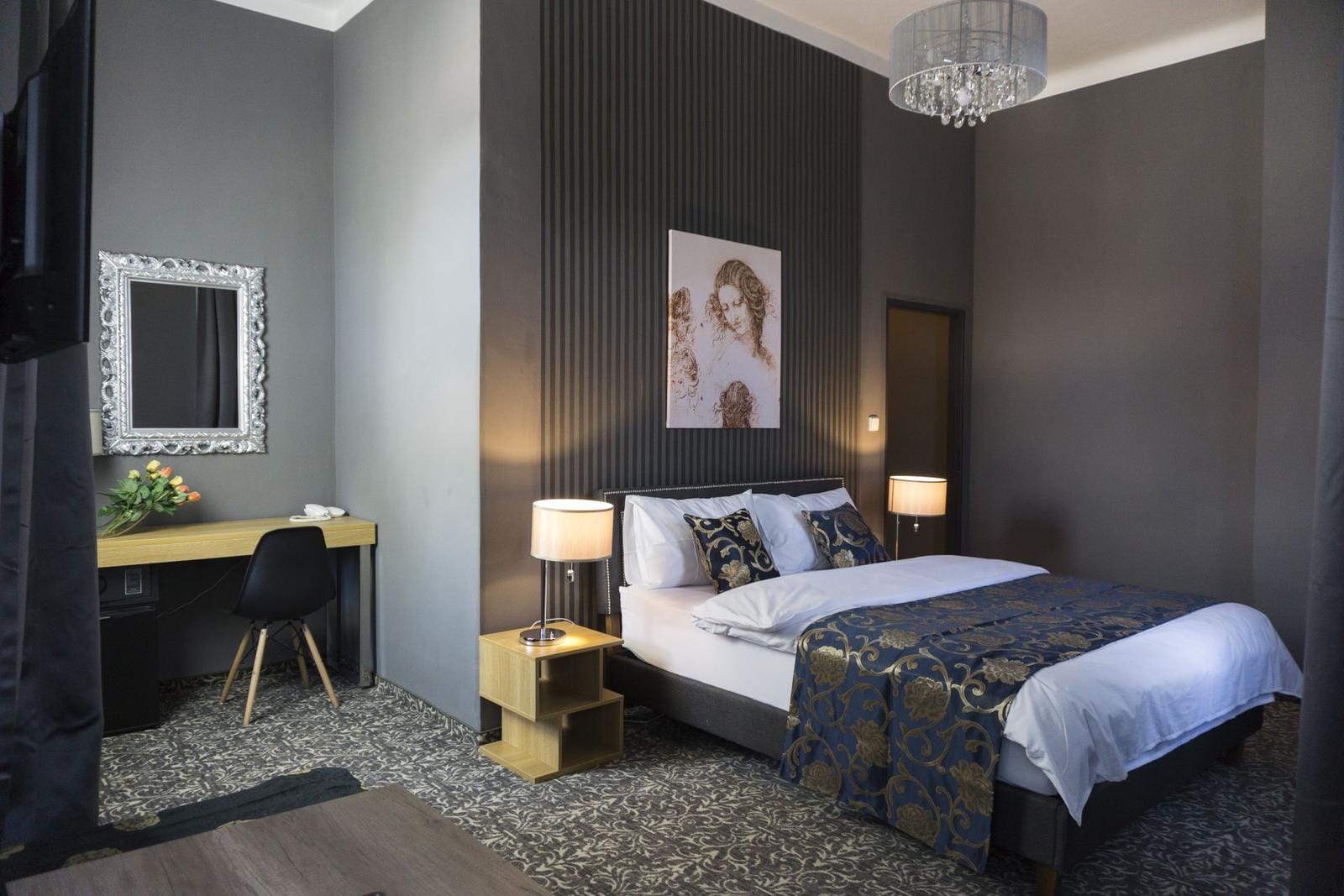 Elegantes Hotelzimmer mit Kingsize-Bett, floralem Teppich und stilvoller Beleuchtung.