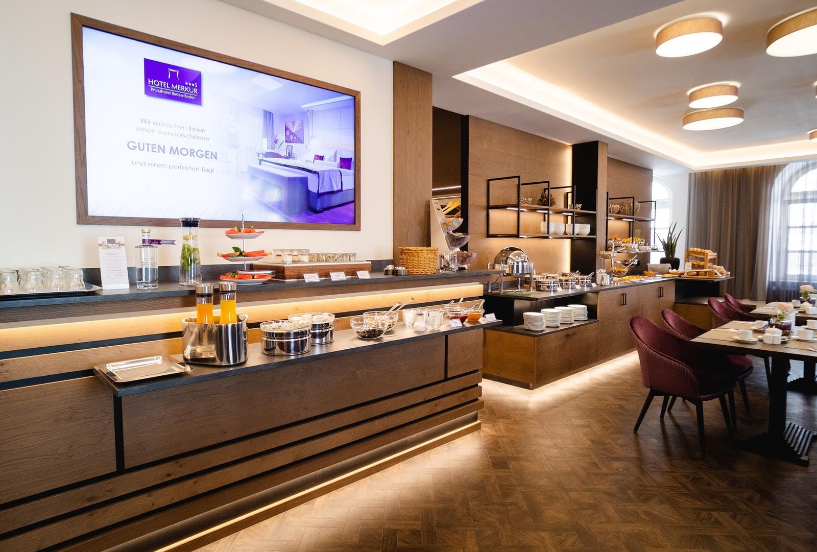 Elegantes Frühstücksbuffet im modernen Hotelrestaurant mit warmem Holzakzent.