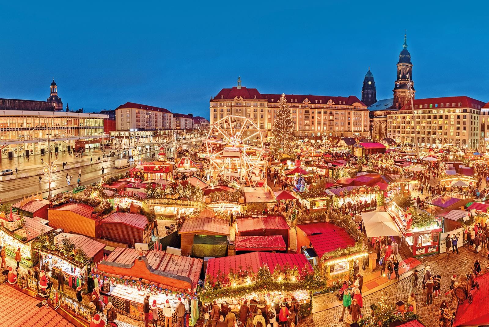 Weihnachtsmarkt in Dresden bei Nacht, mit Lichtern und einem Riesenrad.