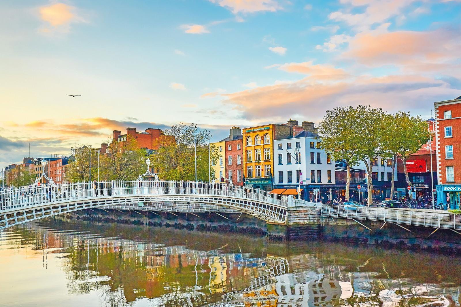 Dublin, Irland: Ha'penny Bridge bei Sonnenuntergang, mit farbenfrohen Häusern am Fluss.