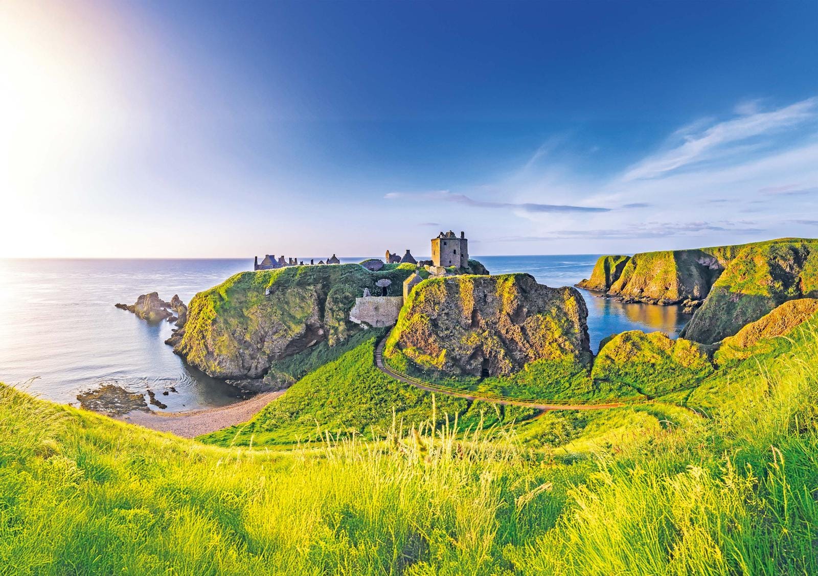 Ruinierte Burg auf grüner Klippe an Schottlands Küste bei sonnigem Wetter.