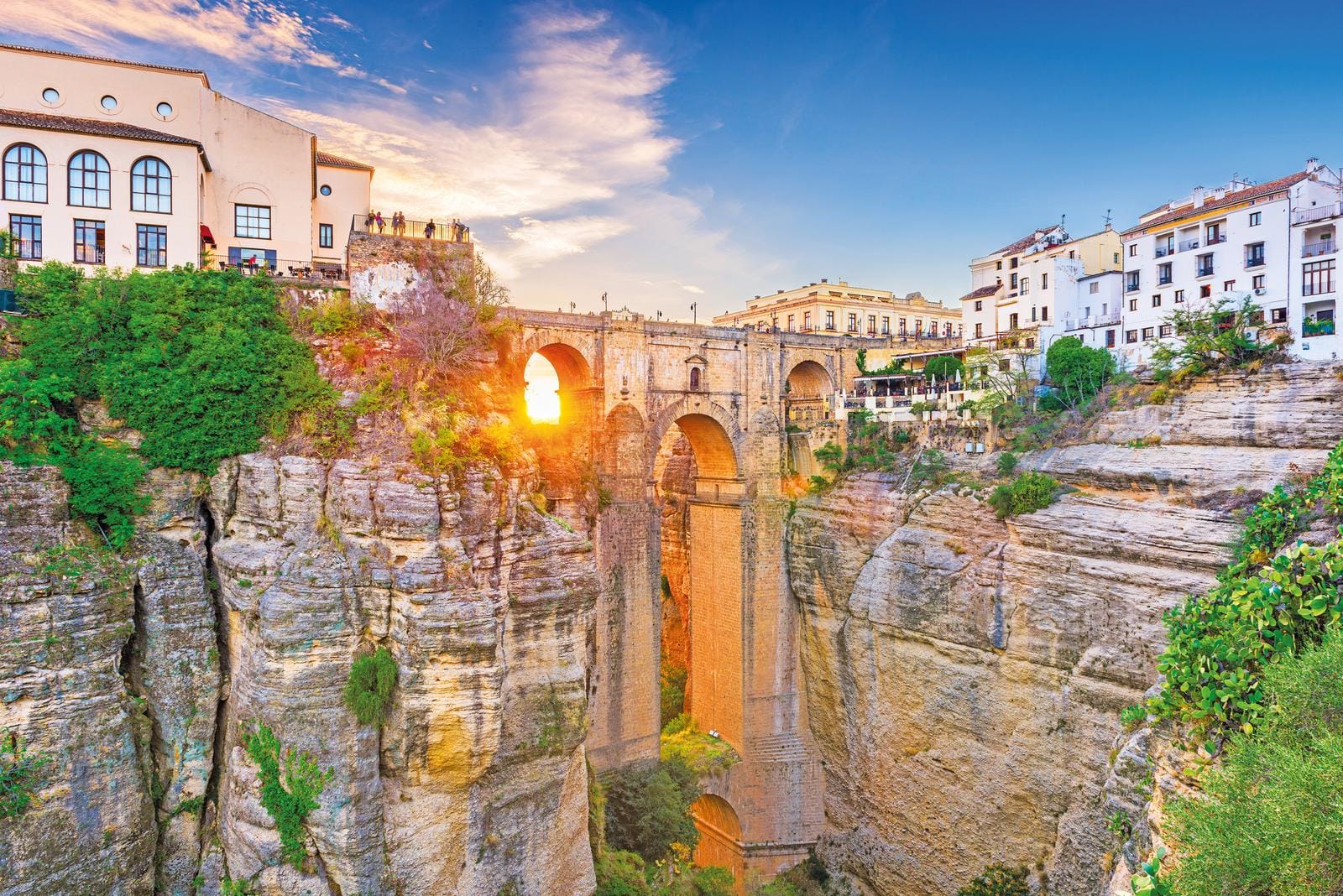 Schlucht mit Brücke und weißen Häusern im Sonnenuntergang, Ronda, Spanien.