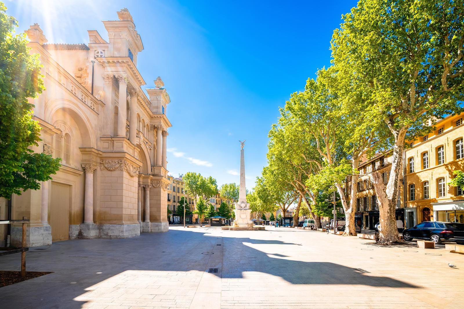 Sonniger Platz in Aix-en-Provence mit klassischer Architektur und Denkmal.