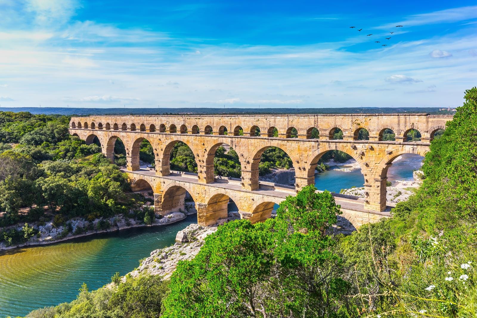 Römisches Aquädukt Pont du Gard, Südfrankreich, über Fluss und üppige grüne Landschaft.