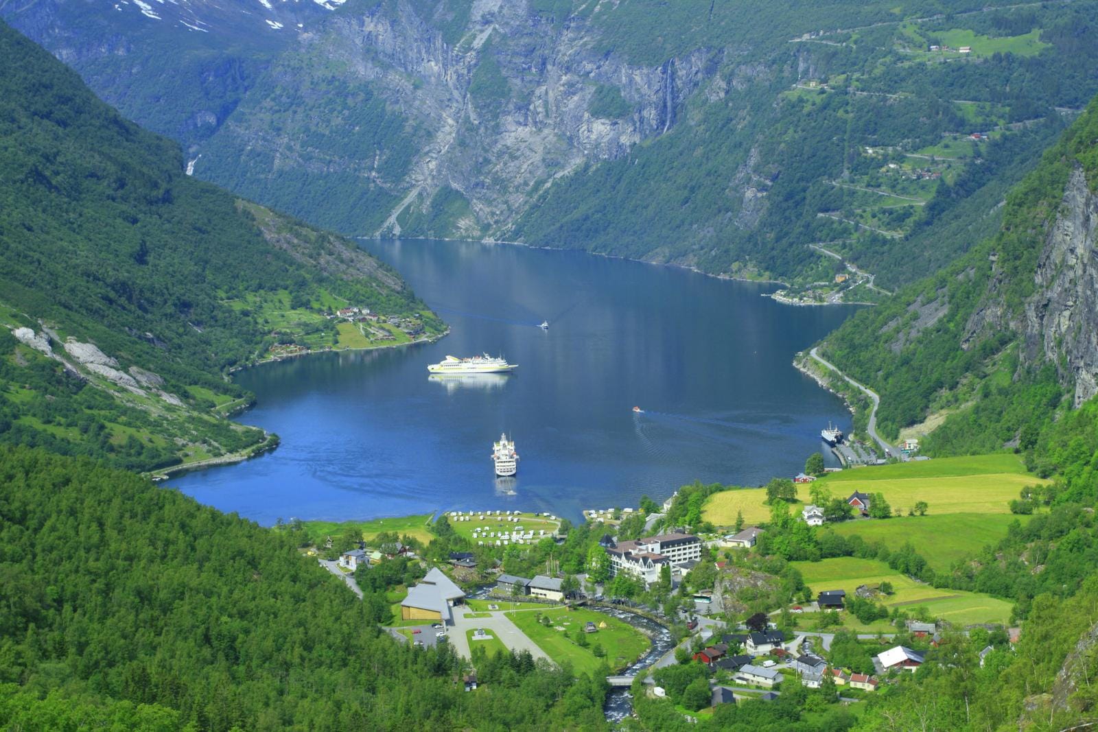 Geirangerfjord mit grünen Bergen entlang des Ufers und blauem Himmel