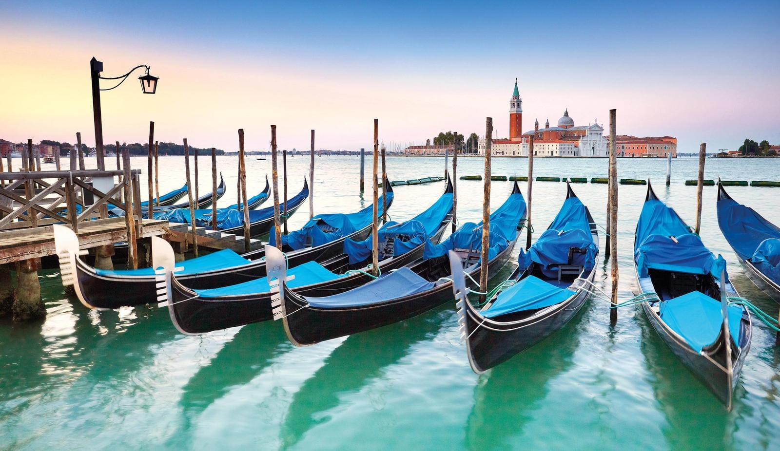 Gondeln vor der Insel San Giorgio Maggiore, Venedig, Italien, bei Sonnenuntergang.