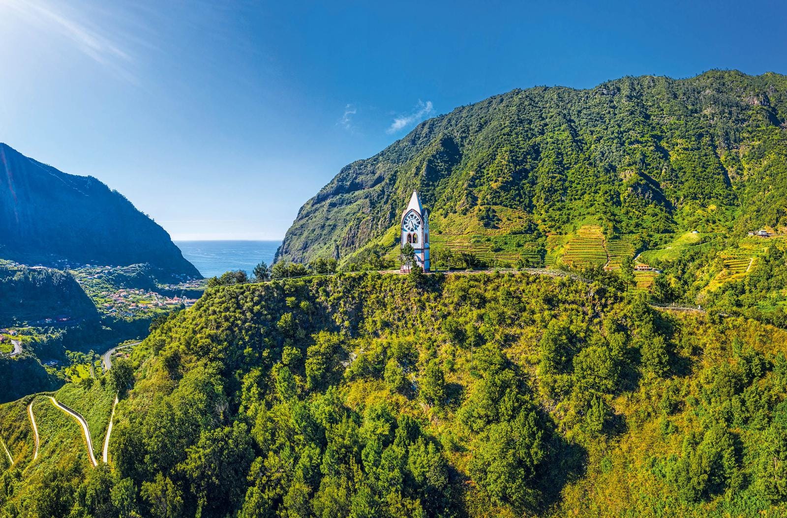 Grünes Bergpanorama mit Kirchenuhr und atemberaubendem Ausblick auf Madeira, Portugal.
