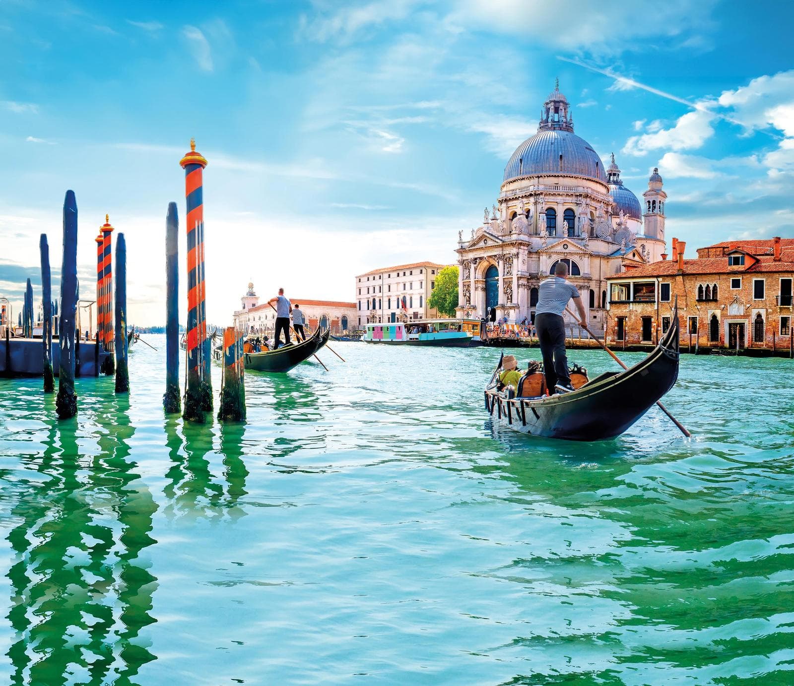 Gondeln vor der Santa Maria della Salute in Venedig, Italien, bei sonnigem Wetter.