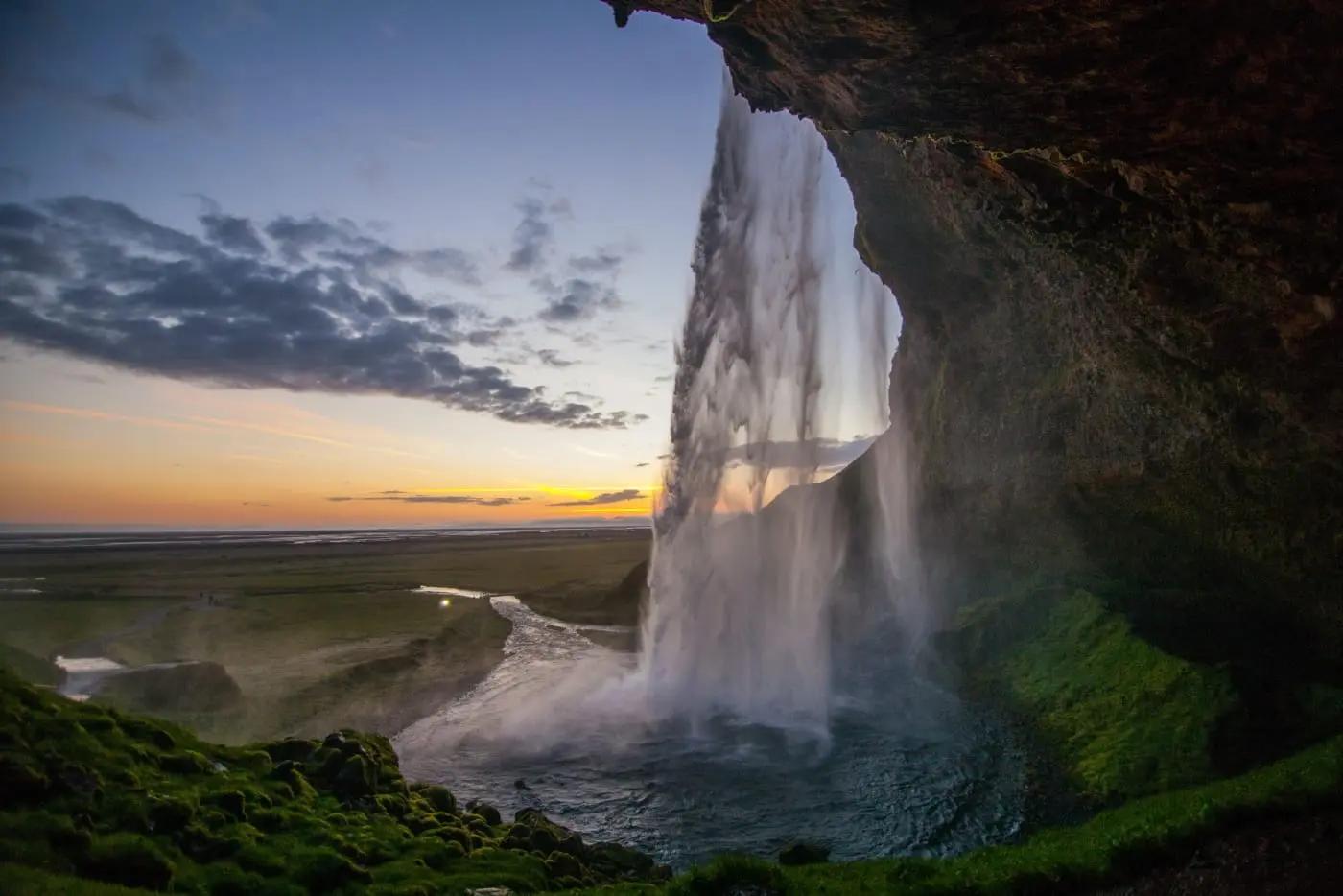 Wasserfall Seljalandsfoss bei Sonnenuntergang in Island, grüne Landschaft, dramatischer Himmel.