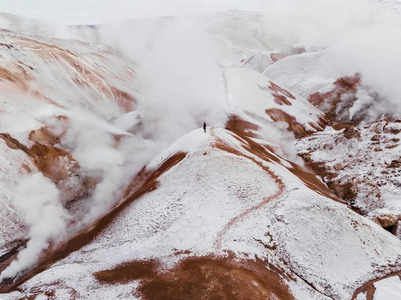 Schneebedeckte heiße Quellen in Islands Kerlingarfjöll mit aufsteigendem Dampf.