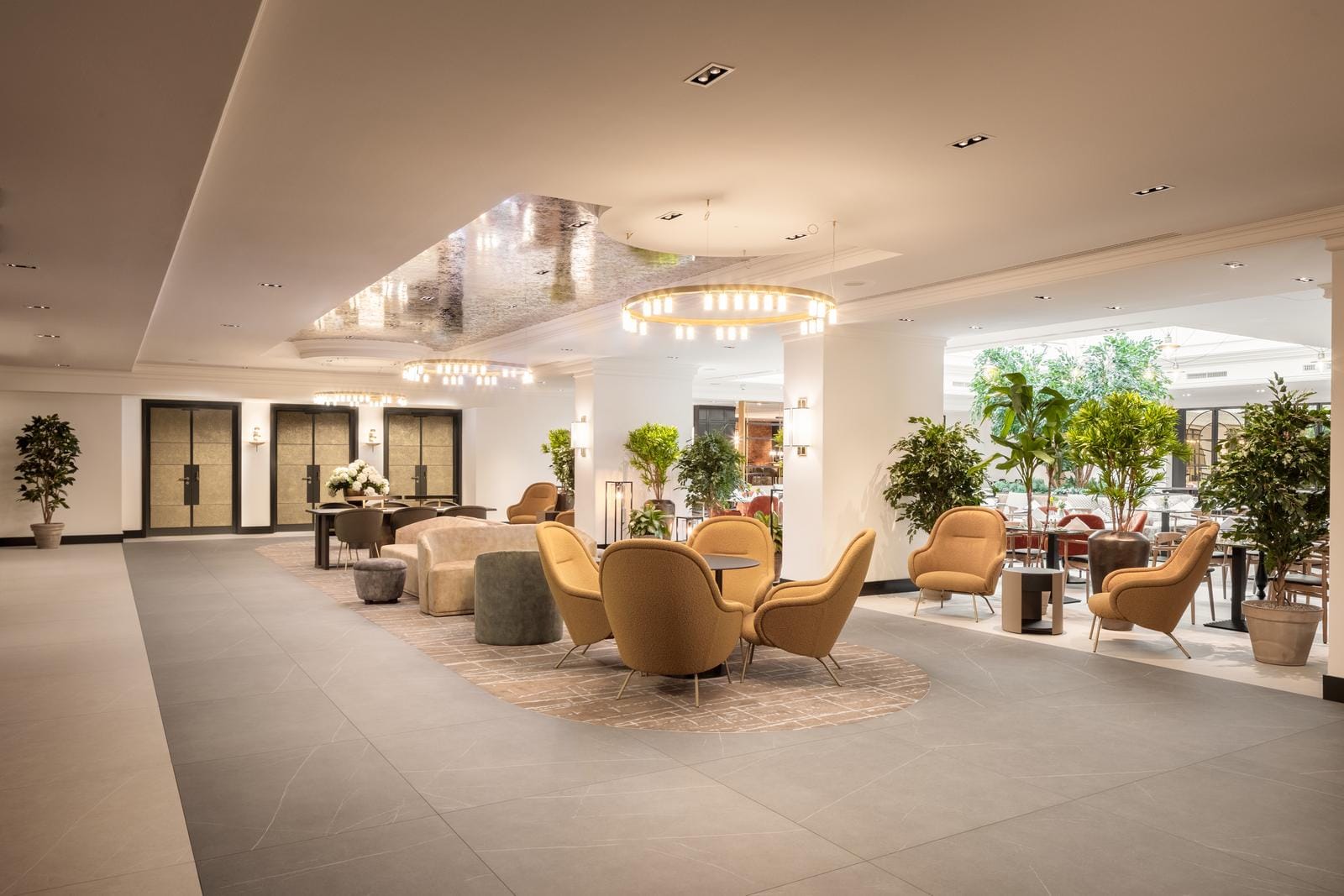Elegante Hotellobby mit beigen Sesseln, Pflanzen und modernen Leuchten.