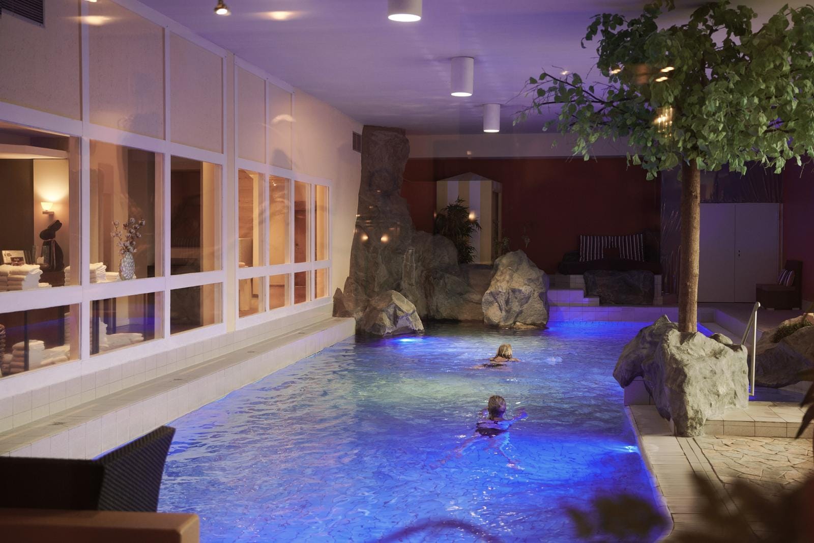Indoor-Pool mit Felsen-Design und blauer Beleuchtung, entspannte Atmosphäre.
