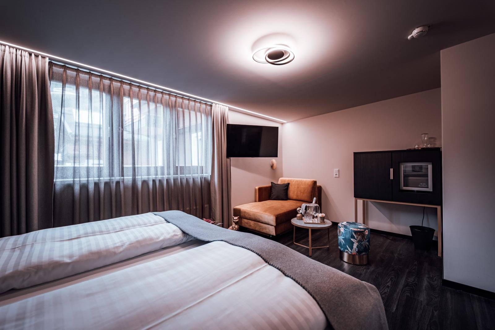 Modernes Hotelzimmer, lichtdurchflutet, mit Doppelbett, gemütlicher Sessel, stilvoll.