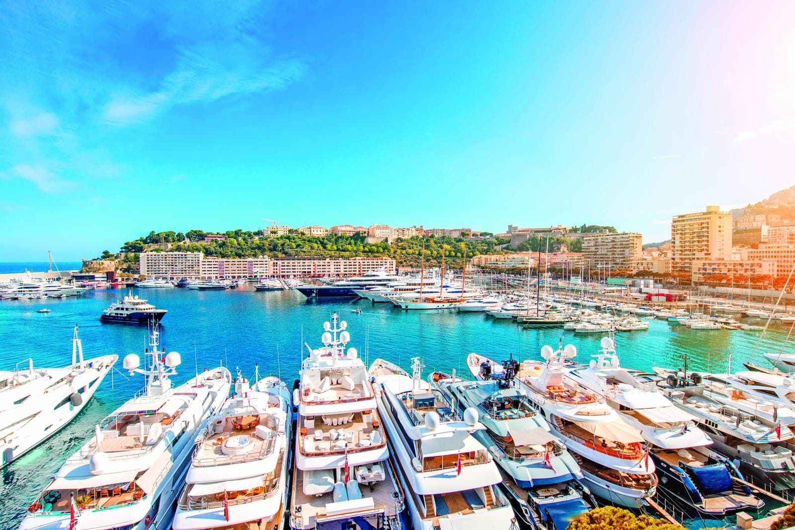 Yachthafen in Monaco, luxuriöse Boote, azurblaues Meer, sonniges Wetter.