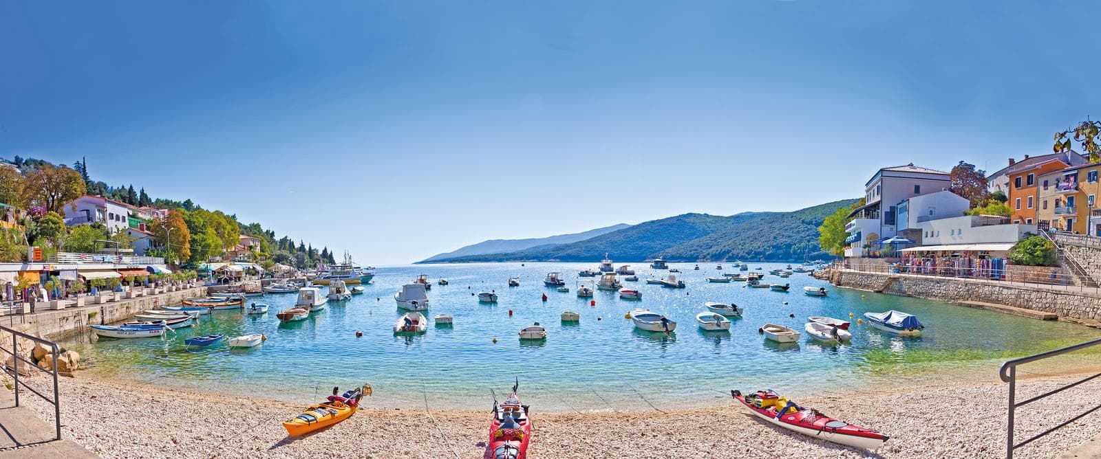 Malerische Küstenstadt in Kroatien mit bunten Häusern und Boote im klaren Wasser.