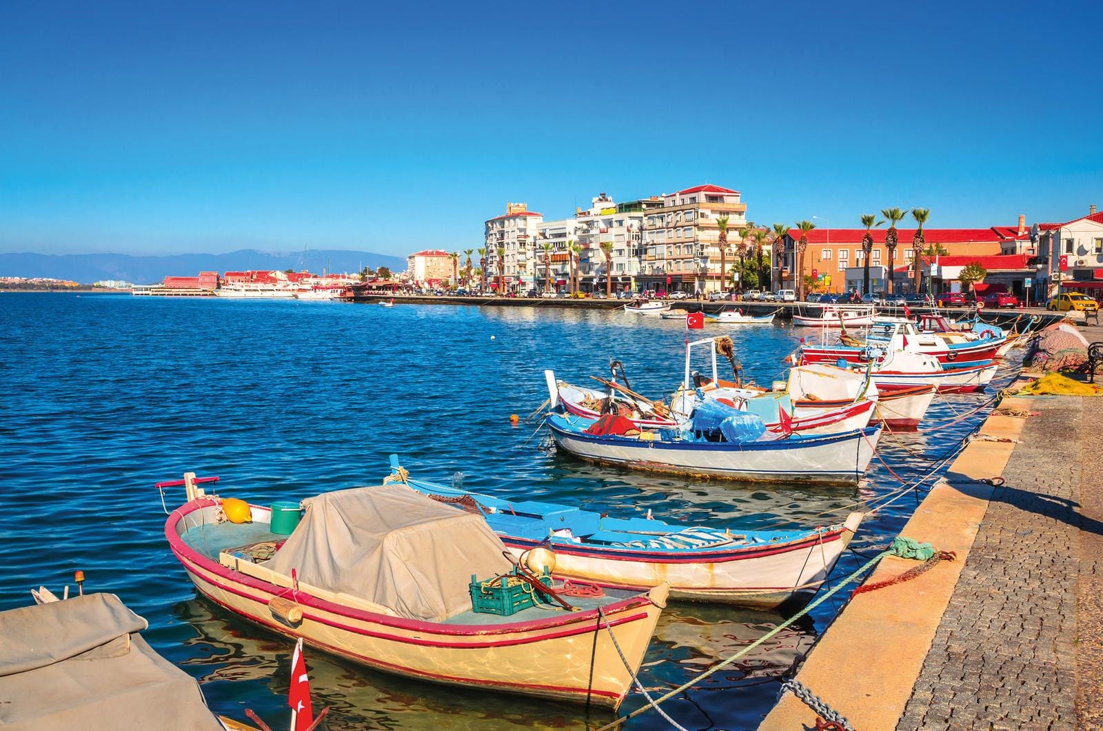 Bunte Fischerboote im Hafen von Izmir, Türkei, an einem sonnigen Tag, mit klarer Sicht.